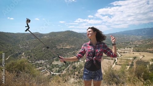 A young beautiful woman using extreme camera at incredible landscapes in Cyprus. Awesome view from the top of the mountain