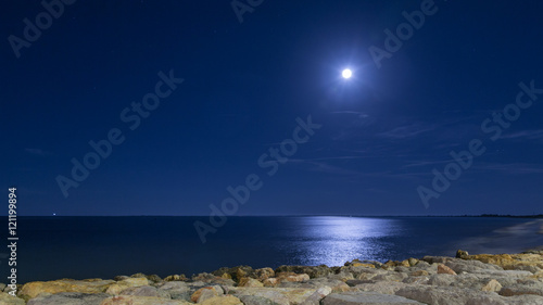 The moon in the sky and lune pathe in the sea. Night. Catalonia, L'Ampolla, Spain
