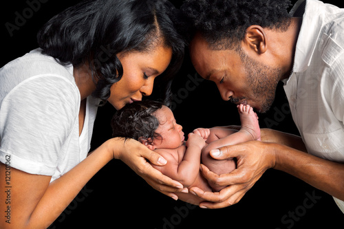 African American Couple Cradles Newborn Daughter Between Them In