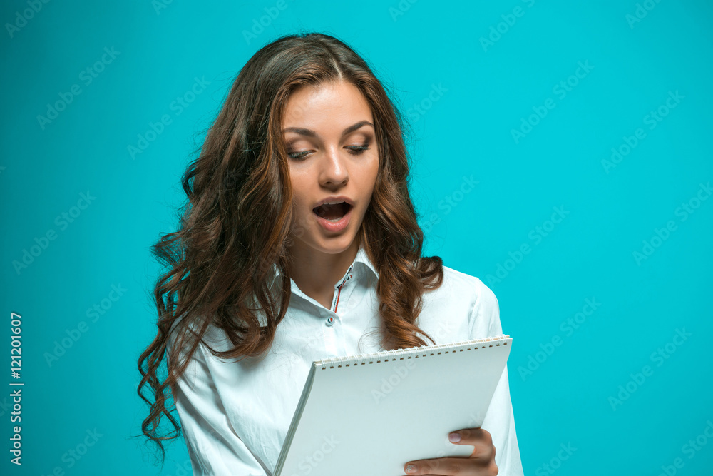 Surprised young business woman with tablet for notes on blue background Surprised young business woman with tablet for notes on blue background