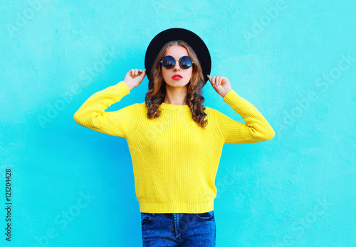 Fashion portrait pretty woman wearing a black hat and yellow kni