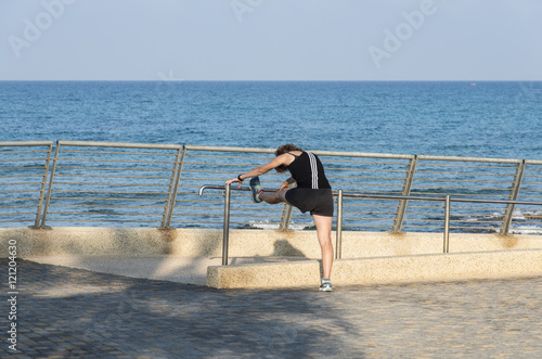 Woman doing stretching exercise, after workout in the sea