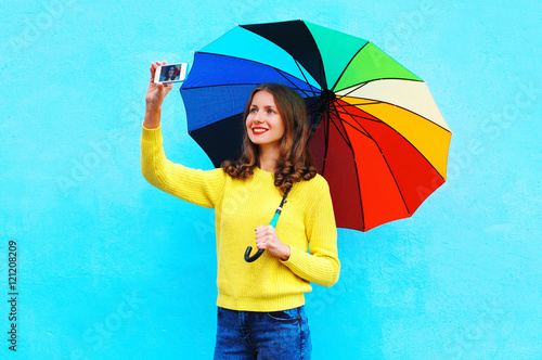 Happy smiling young woman with autumn colorful umbrella taking p