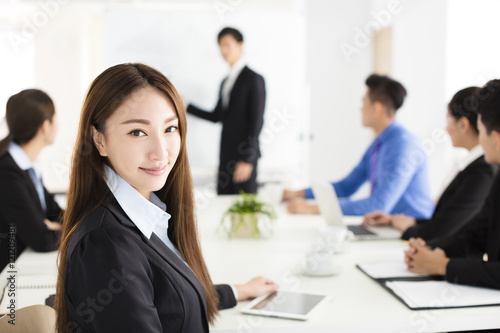 Smiling businesswoman looking at camera with  colleague