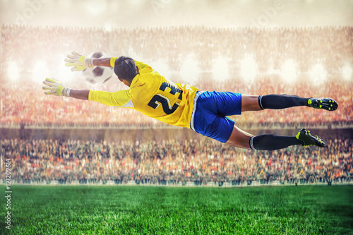 soccer goalkeeper flying to catches the ball in the stadium