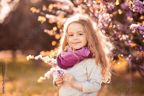 Smiling kid girl 4-5 year old holding flower wearing casual clothes outdoors. Looking at camera. Childhood.