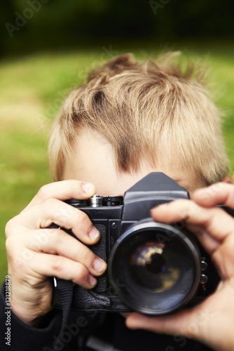 Child blond boy with vintage photo film camera photographing