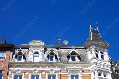 Historic Renaissance Revival architecture in the Frankenberger Quarter, Aachen, Germany with a townhouse with ornate stone carving, dormer windows and turret against a blue sky