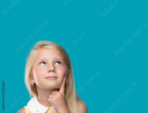 Fototapeta The little girl is thinking about something on a blue background