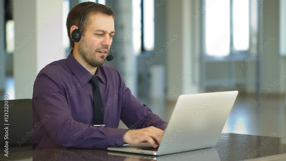 Focus on a joyful call centre agent with his headset Focus on a joyful call centre agent with his headset