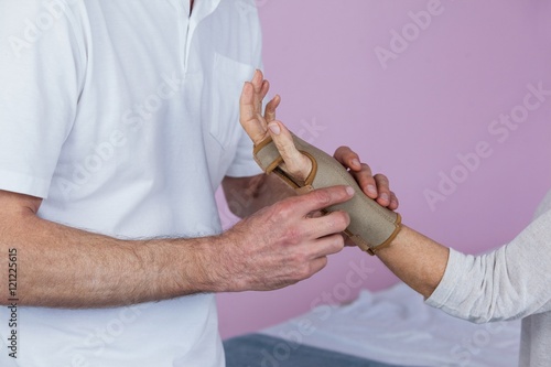 Mid section of physiotherapist examining a senior woman's wrist