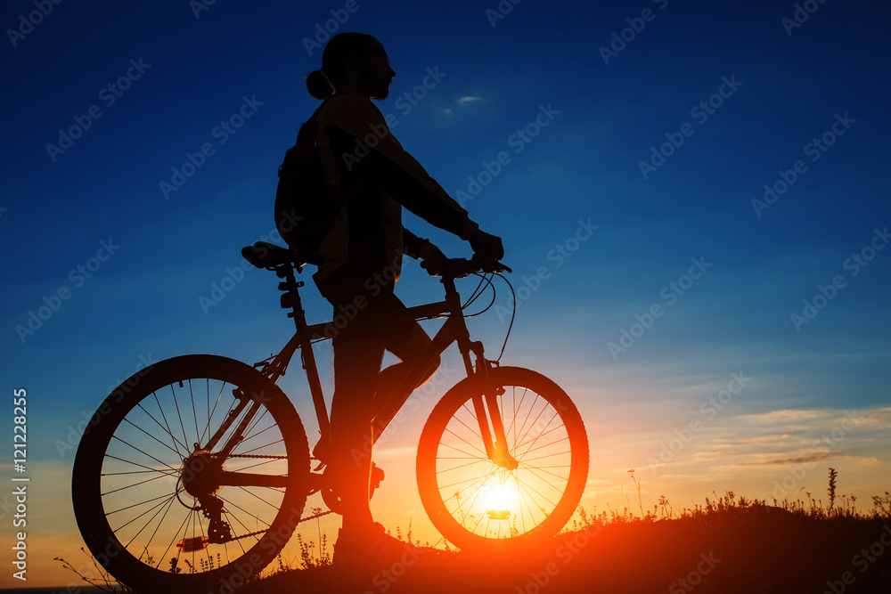 Obraz premium Silhouette of cyclist and a bike on sky background