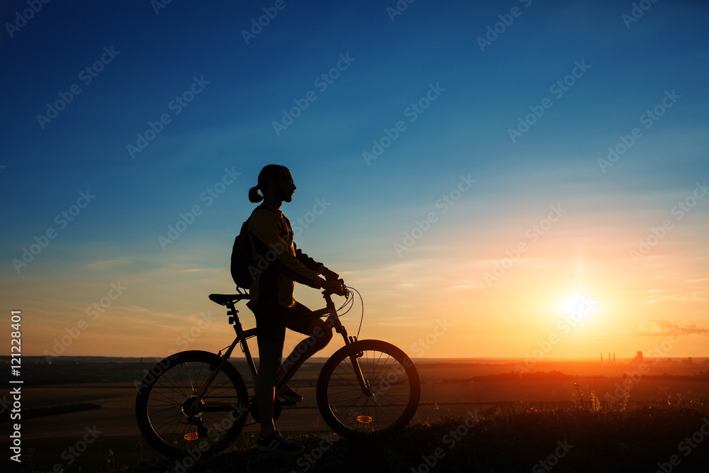 Silhouette of cyclist and a bike on sky background Silhouette of cyclist and a bike on sky background