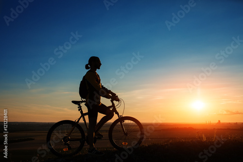 Silhouette of cyclist and a bike on sky background © Aleksey