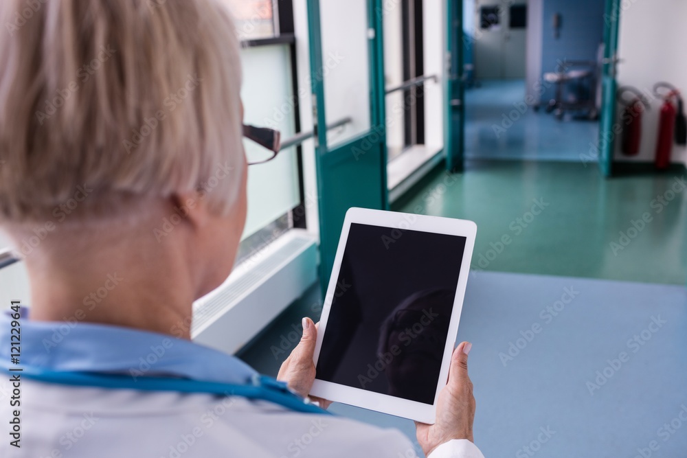 Doctor using digital tablet in corridor Doctor using digital tablet in corridor