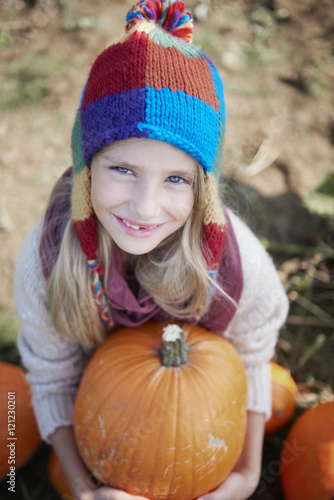 Little blonde girl with big pumpkin