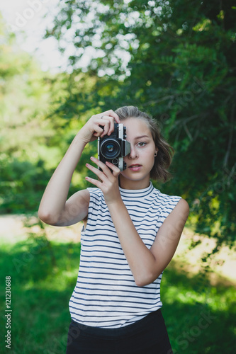 teenage girl making photo with film camera in the park