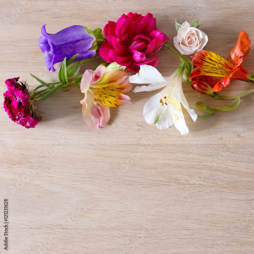 Creative arrangement made of different flowers on wooden background with space for text. © Magryt