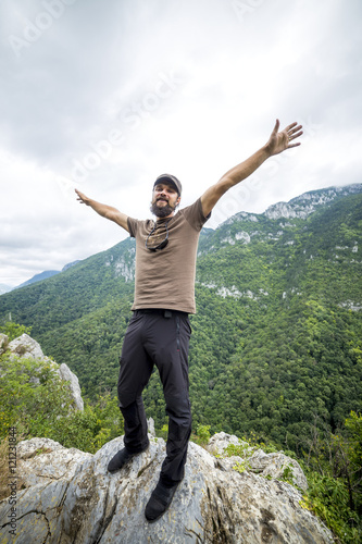 Hiker standing on top of a mountain with raised arms