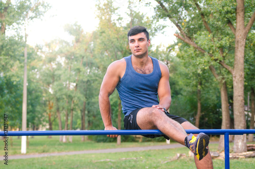 fitness, sport, exercising, training and lifestyle concept - young man doing triceps dip on parallel bars outdoors.