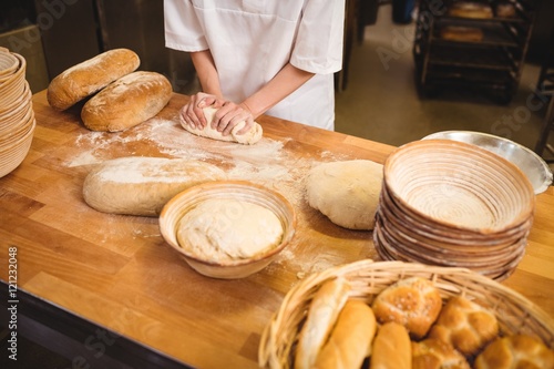 Mid-section of female baker kneading a dough