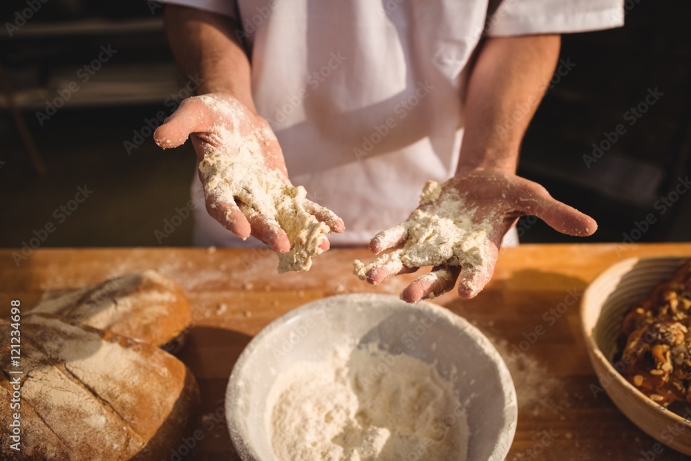 Fototapeta premium Mid-section of baker mixing flour by hand