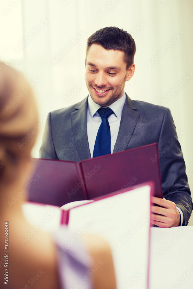 smiling young man looking at menu at restaurant smiling young man looking at menu at restaurant