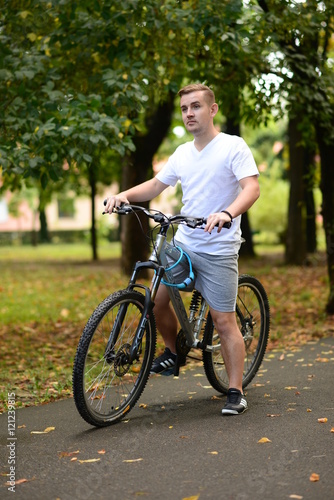 Blonde attractive young man cycling in the park 