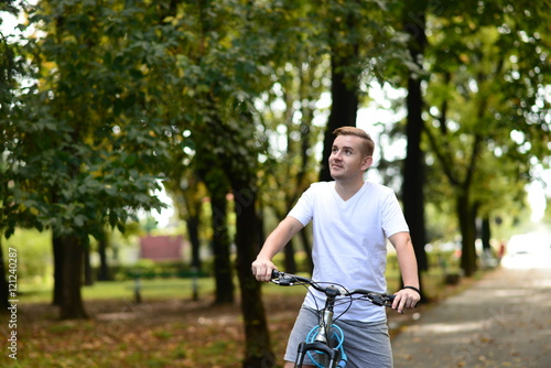 Blonde attractive young man cycling in the park  © cristinaindrie