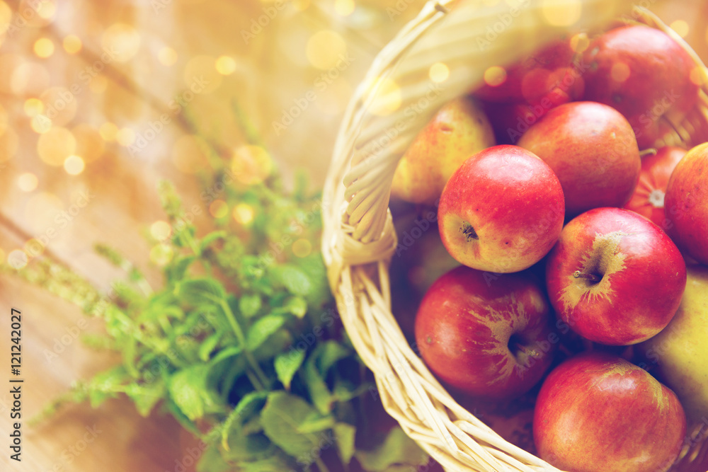 close up of basket with apples and herbs on table close up of basket with apples and herbs on table