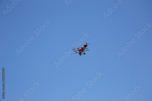 Red WWI Fokker Triplane in Flight on clear blue Sky