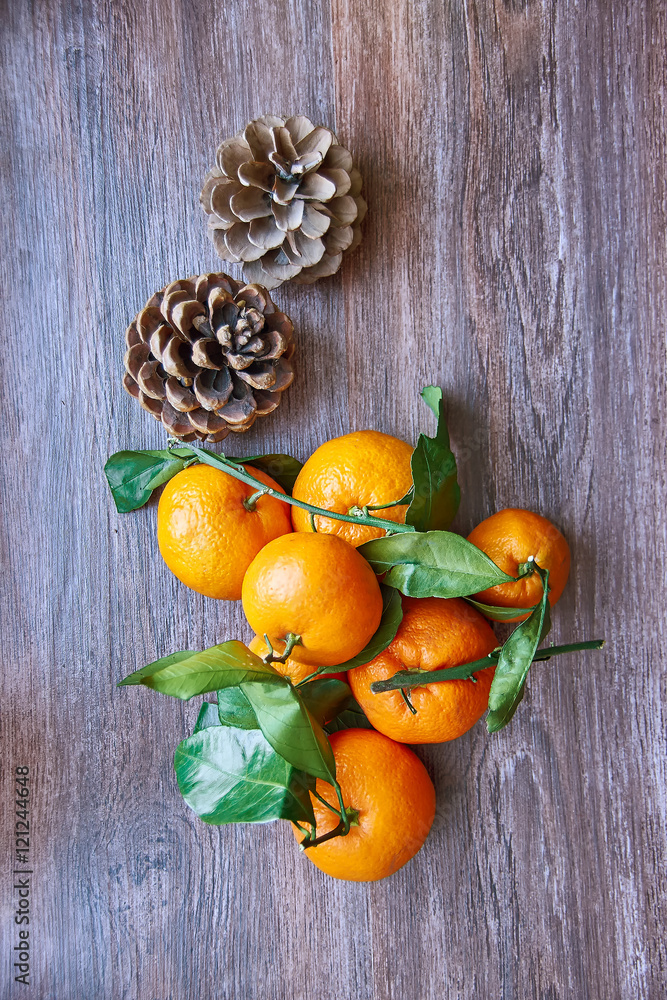 Winter still life of ripe tangerines with branches and pine cones on a wooden table. Top view Winter still life of ripe tangerines with branches and pine cones on a wooden table. Top view