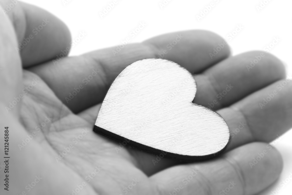 Fototapeta premium Close up macro man hand holding wooden heart, love symbol on white background, black and white effect with selective focus