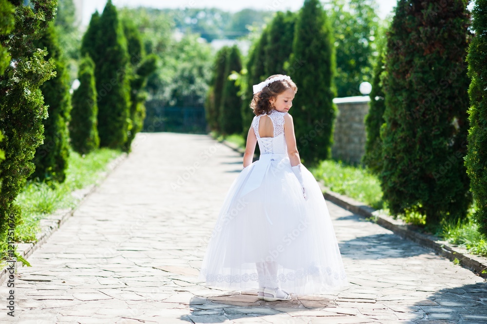 Portrait of cute little girl on white dress and wreath of first holy communion background thuja alley Portrait of cute little girl on white dress and wreath of first holy communion background thuja alley