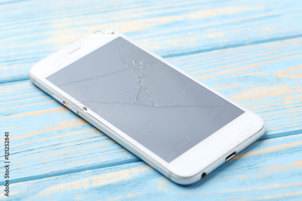 Broken smartphone on a blue wooden table Broken smartphone on a blue wooden table