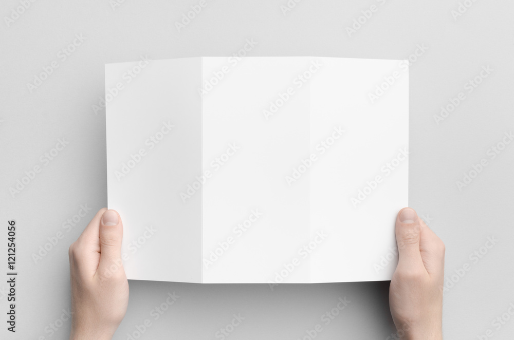 A4 Tri-Fold Brochure Mock-Up - Male hands holding a blank tri-fold on a gray background. A4 Tri-Fold Brochure Mock-Up - Male hands holding a blank tri-fold on a gray background.