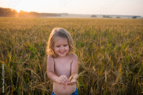 Симпатичная трехлетняя девочка держит колоски и улыбается