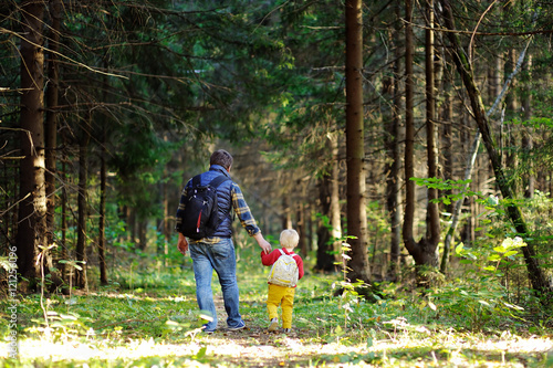 Father and his son walking during the hiking activities in forest