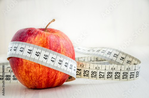 Read Apple and Tape Measure on a Table with Wooden Background. 