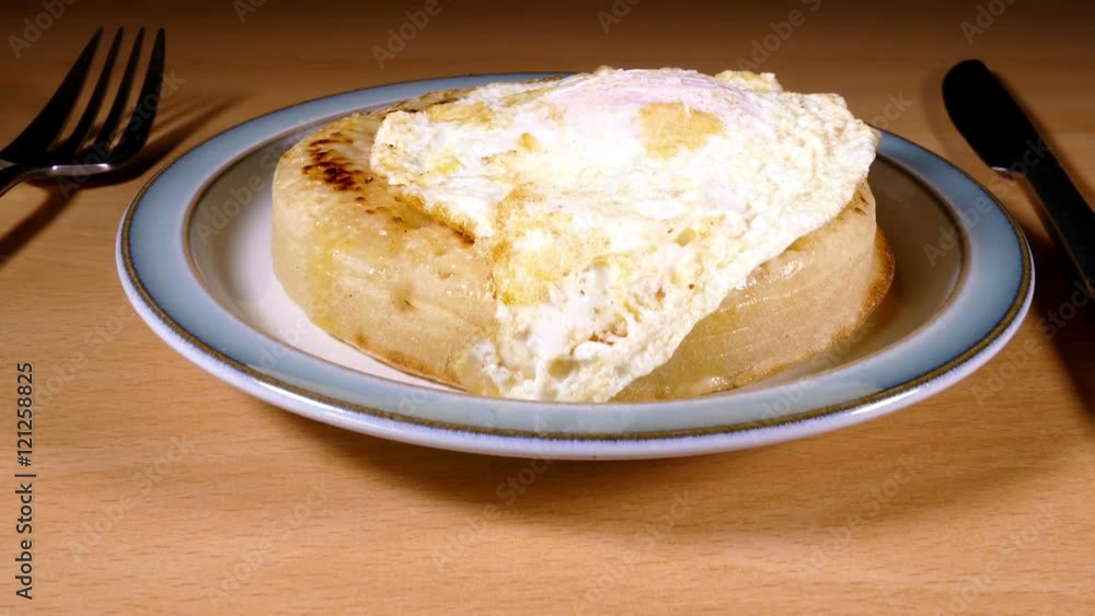 Forward slide shot past the salt and pepper to a fried egg on top of a melted butter crumpet on a plate. Forward slide shot past the salt and pepper to a fried egg on top of a melted butter crumpet on a plate.