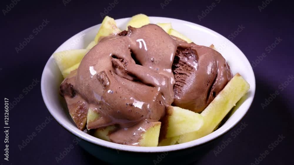 Timelapse of chocolate ice cream melting over sliced apple in a bowl. Timelapse of chocolate ice cream melting over sliced apple in a bowl.