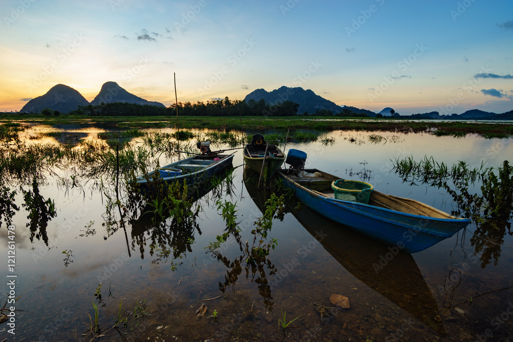 Beautiful majestic sunrise by the lakeside with fishing boats. Nature rural landscape.