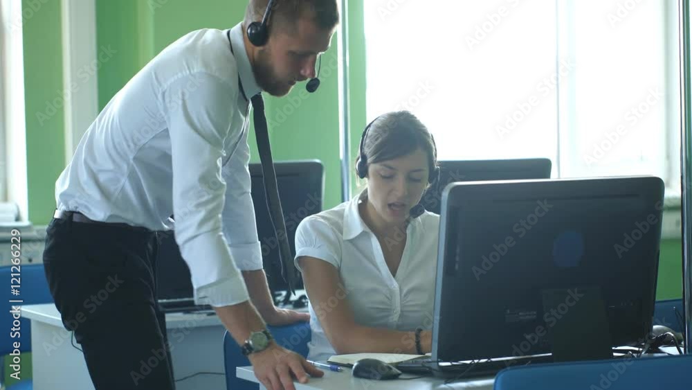 Phone operator working at call centre office helping hiss colleague. Phone operator working at call centre office helping hiss colleague.