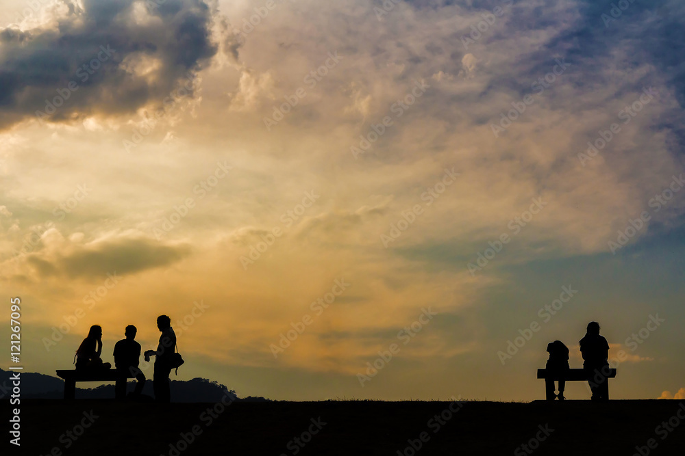 Silhouette of people sitting on bench in evening