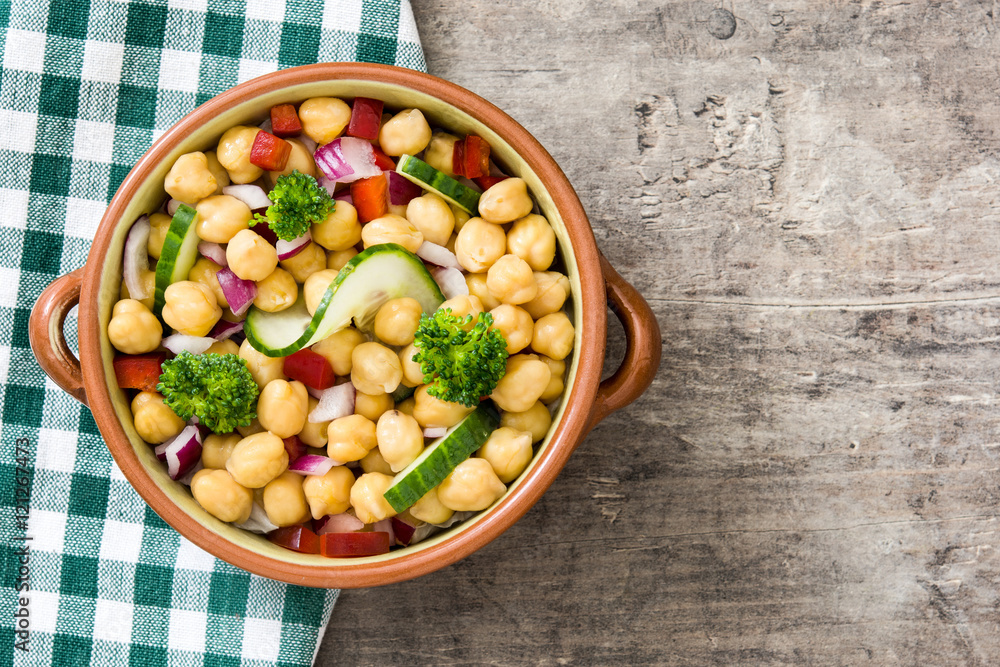 Chickpea salad in bowl on wooden background

