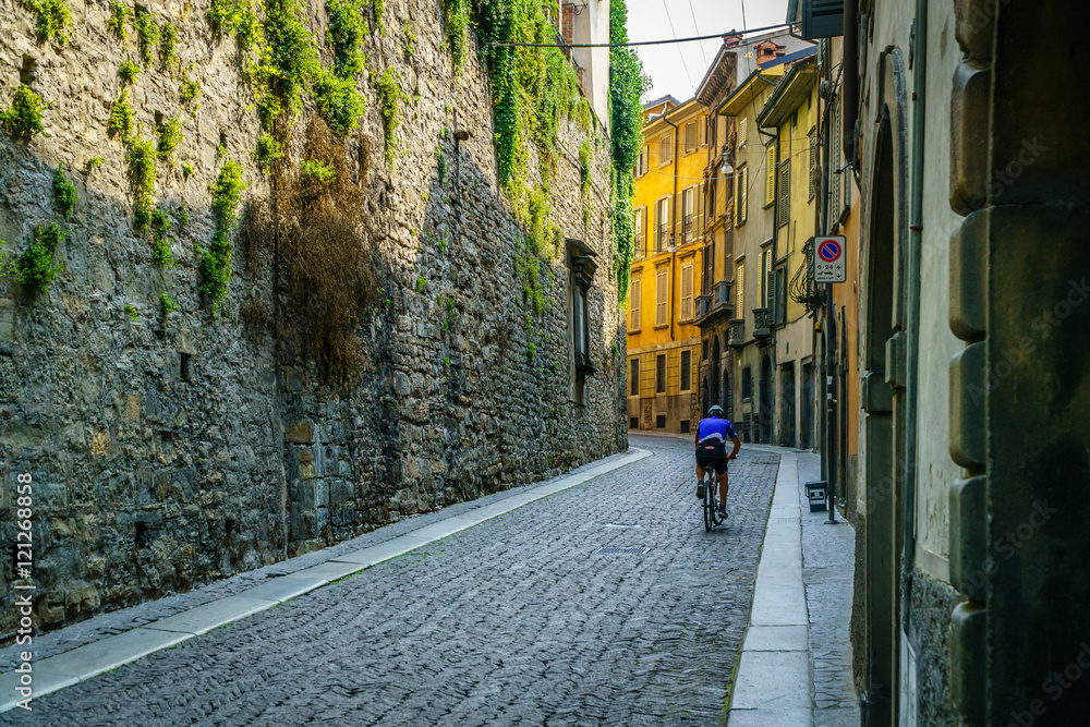 Obraz premium Cyclist riding on typical street of Bergamo italy