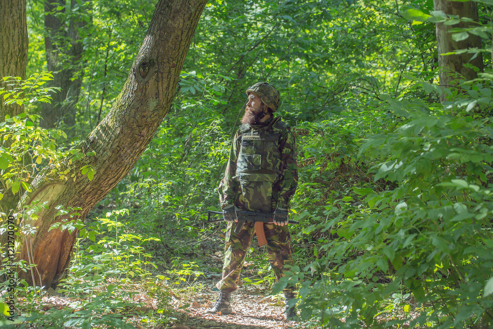 Bearded soldier with the gun in the forest Bearded soldier with the gun in the forest