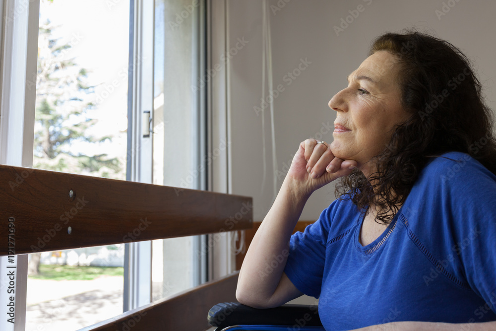 woman on a wheelchair lookinf for a window woman on a wheelchair lookinf for a window