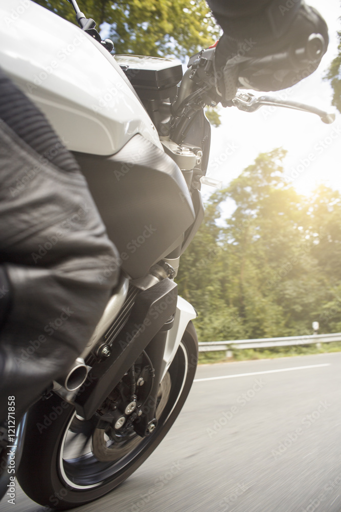 Fototapeta premium Motorradfahrer fährt auf Straße im Sommer