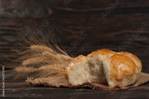 freshly baked bread with sesame seeds, wheat ears, vintage wooden background photo